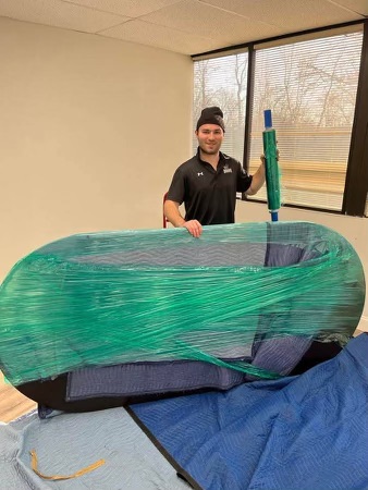 Professional mover wrapping office furniture in protective material